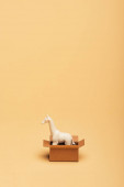 Bílá hračka žirafa v lepenkové krabici na žlutém pozadí, koncept dobrých životních podmínek zvířat