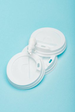 Oyuncak kutup ayısının mavi arka plandaki plastik kahve kapaklarının en üst görüntüsü, hayvan refahı konsepti