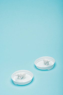 Beyaz oyuncak kutup ayıları mavi arka planda plastik kahve kapakları, hayvan refahı konsepti