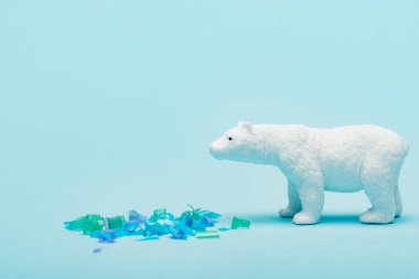 Mavi arka planda plastik parçaların yanında oyuncak kutup ayısı, hayvan refahı konsepti