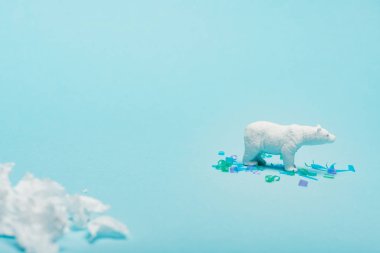 Mavi arka planda polietilen ve plastik parçaları olan oyuncak kutup ayısının seçici odak noktası, hayvan refahı kavramı