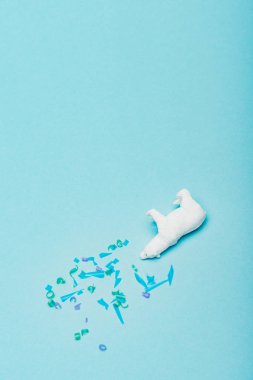 Mavi arka planda plastik parçaları olan oyuncak kutup ayısı manzarası, hayvan refahı kavramı