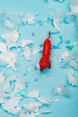 Kırmızı oyuncak aslanın mavi arka plandaki plastik çöpten görünüşü, hayvan refahı kavramı