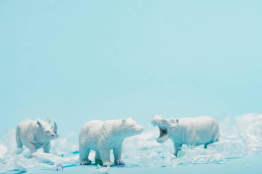 Beyaz su aygırı, gergedan ve ayının oyuncakları mavi arka planda plastik çöp, hayvan refahı konsepti