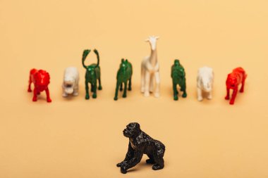 Selective focus of gorilla with colored toy animals on yellow background, extinction of animals concept clipart