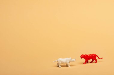 Toy rhinoceros and tiger on yellow background, animal welfare concept clipart