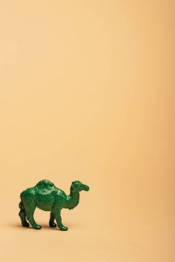 Green toy camel on yellow background, animal welfare concept clipart