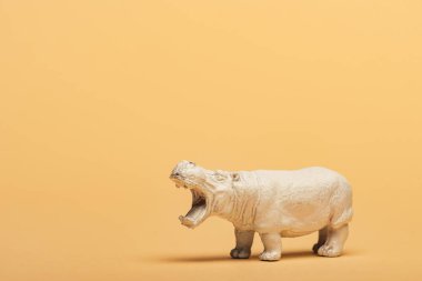 White toy hippopotamus on yellow background, animal welfare concept clipart