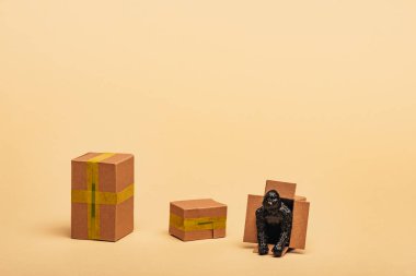 Toy gorilla in cardboard container with boxes on yellow background, animal welfare concept clipart
