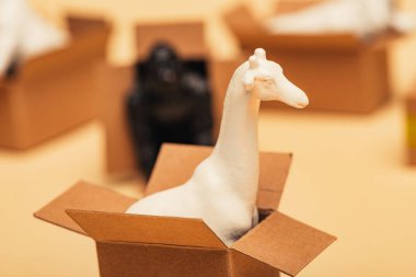 Selective focus of giraffe and toy animals in cardboard boxes on yellow background, animal welfare concept clipart