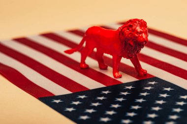 Red toy lion on american flag on yellow background, animal welfare concept clipart