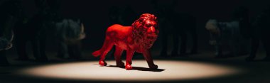 Kırmızı oyuncak aslanın panoramik çekimi sahne ışıkları altında, arka planda hayvanlar, oy verme konsepti