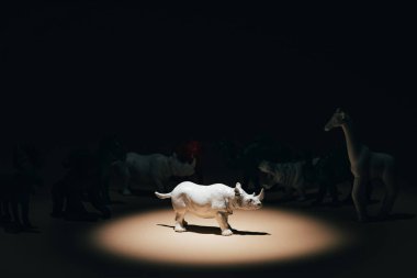 Beyaz oyuncak gergedanlar sahne ışıkları altında, arka planda hayvanlar, oy verme konsepti