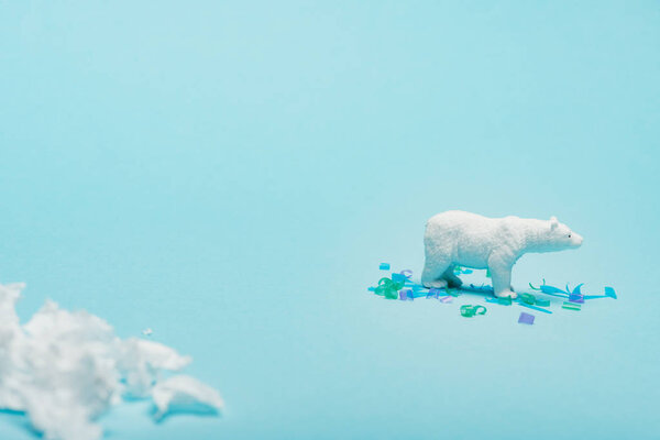 Селективный фокус игрушечного белого медведя с полиэтиленом и пластиковыми деталями на синем фоне, концепция благополучия животных
