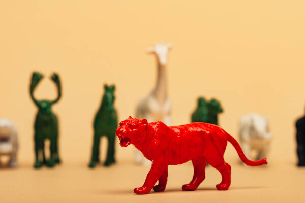 Selective focus of red tiger with colored toy animals on yellow background, extinction of animals concept