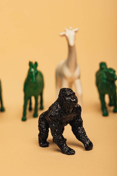 Selective focus of gorilla with colored toy animals on yellow background, extinction of animals concept