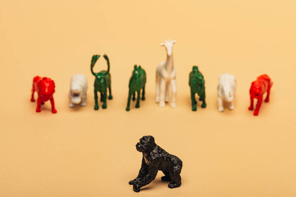 Selective focus of gorilla with colored toy animals on yellow background, extinction of animals concept