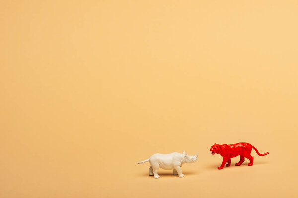 Toy rhinoceros and tiger on yellow background, animal welfare concept