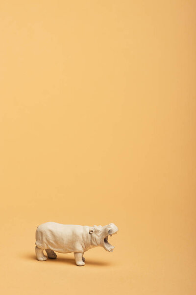 White toy hippopotamus on yellow background, animal welfare concept