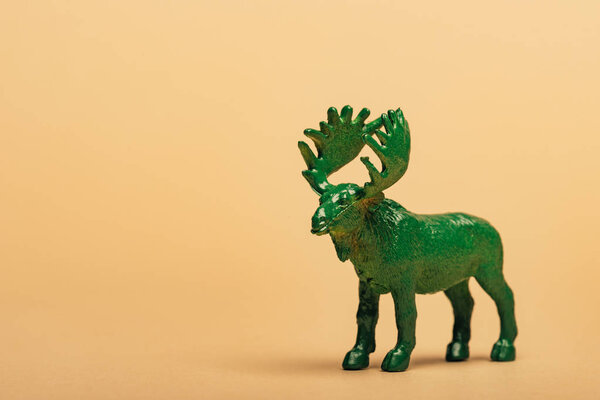 Green toy moose on yellow background, animal welfare concept