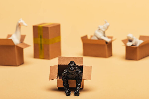 Selective focus of animal toys in cardboard boxes on yellow background, animal welfare concept