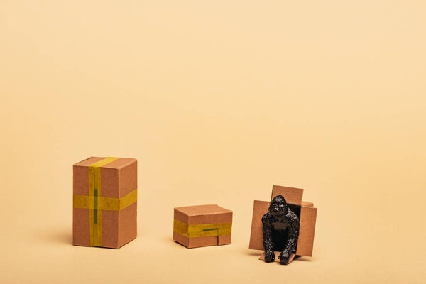 Toy gorilla in cardboard container with boxes on yellow background, animal welfare concept