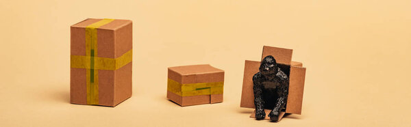 Panoramic shot of toy gorilla in cardboard container with boxes on yellow background, animal welfare concept