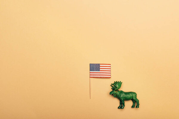 Top view of green toy moose with american flag on yellow background, animal welfare concept