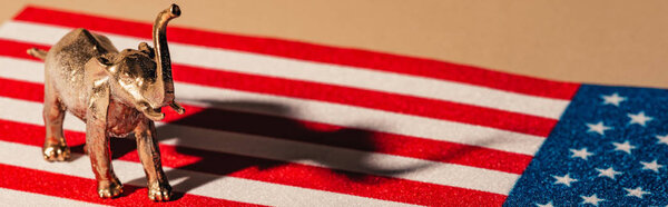 Panoramic shot of golden toy elephant with shadow on american flag, animal welfare concept