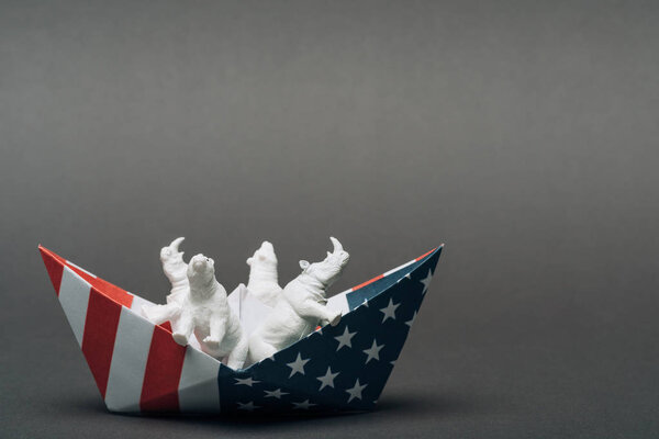Toy animals in paper boat from american flag on grey background, animal welfare concept