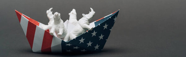 Panoramic shot of toy animals in paper boat from american flag on grey background, animal welfare concept