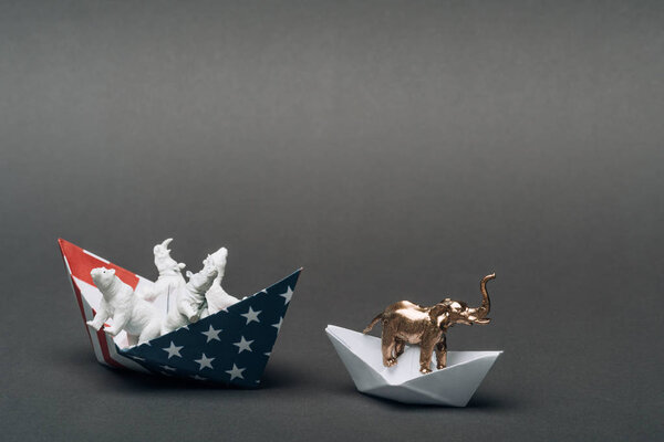 Toy elephant in paper boat and animals in boat from american flag on grey background, animal welfare concept