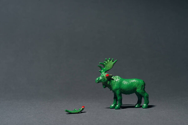 Зеленый игрушечный муз с рогом на сером фоне, концепция охоты на рога
