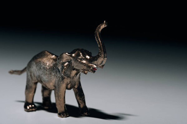 Golden toy elephant with blood on tusks on grey background, hunting for tusks concept