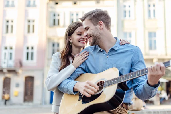 Knappe Man Spelen Akoestische Gitaar Buurt Gelukkig Vriendin Straat — Stockfoto