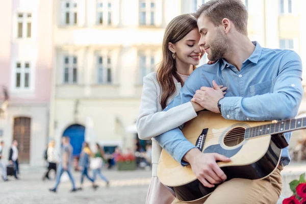 Menina Feliz Abraçando Namorado Segurando Guitarra Acústica Rua — Fotografia de Stock