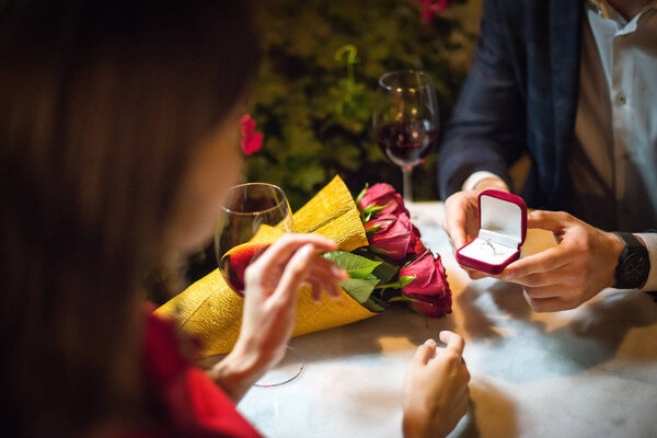 частичный взгляд на мужчину, подарившего обручальное кольцо девушке во время предложения руки и сердца
