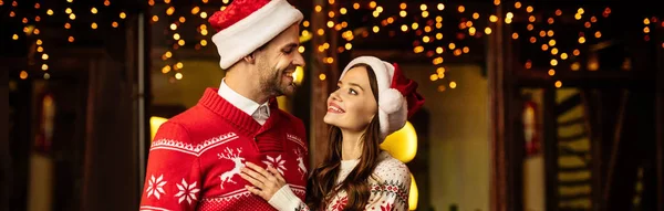 Plano Panorámico Feliz Pareja Joven Suéteres Calientes Sombreros Santa Sonriendo —  Fotos de Stock