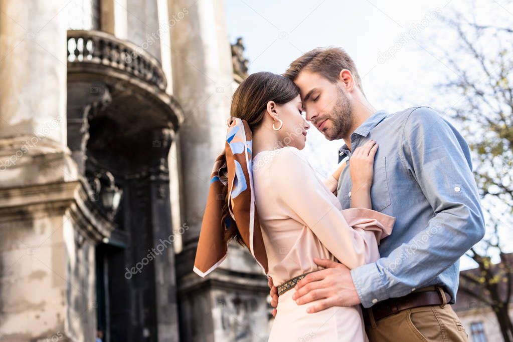 happy, young couple of tourists embracing with closed eyes on street