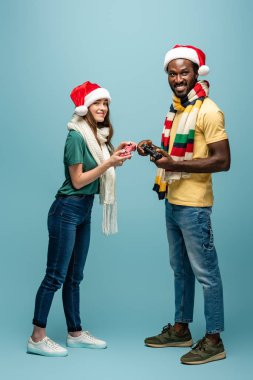 Kyiv, Ukrayna - 22 Ağustos 2019: Noel Baba şapkası ve eşarplı, elinde joystickle gülümseyen bir çift.