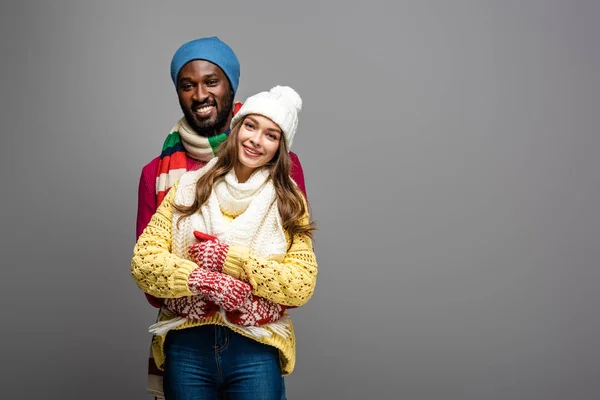 Feliz Casal Interracial Inverno Roupa Abraçando Fundo Cinza — Fotografia de Stock