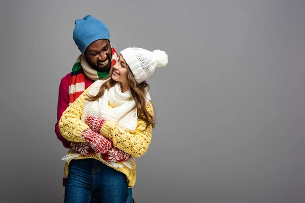 Feliz Casal Interracial Inverno Roupa Abraçando Fundo Cinza — Fotografia de Stock