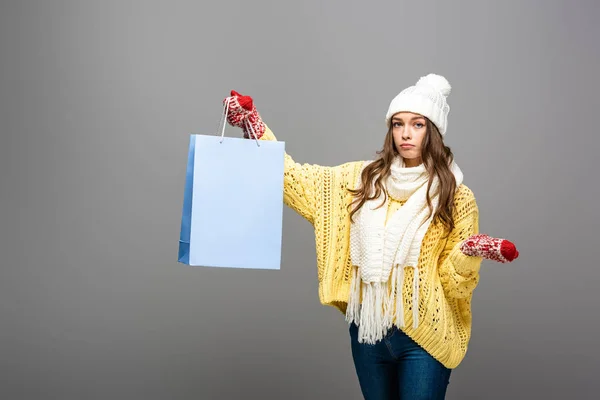 灰色の背景にショッピングバッグ付きの冬服の悲しい女性 — ストック写真