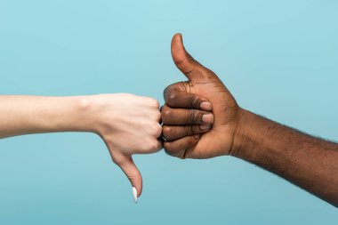 cropped view of interracial couple showing thumbs up isolated on blue clipart