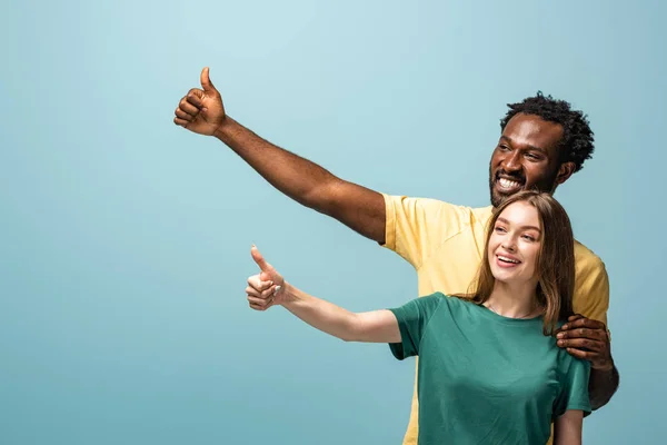 Mavi Arka Planda Parmak Gösteren Mutlu Irklar Arası Bir Çift — Stok fotoğraf