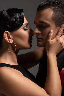 Gri renkte tango yaparken güzel bir dansçı partner öpüyor.