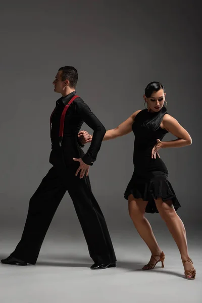 Elegante Casal Dançarinos Roupas Pretas Realizando Tango Fundo Cinza — Fotografia de Stock