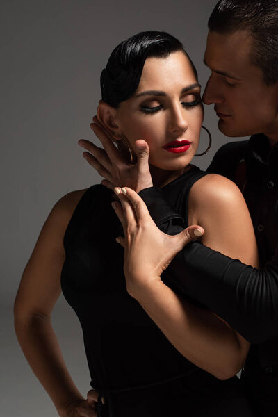 sensual dancer hugging passionate partner while performing tango isolated on grey