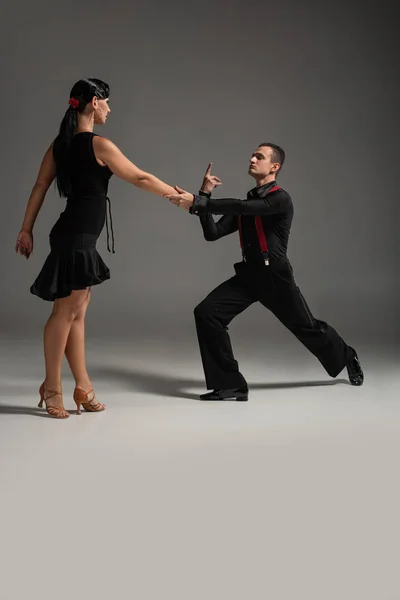 Pareja Expresiva Bailarines Ropa Negra Realizando Tango Sobre Fondo Gris — Foto de Stock