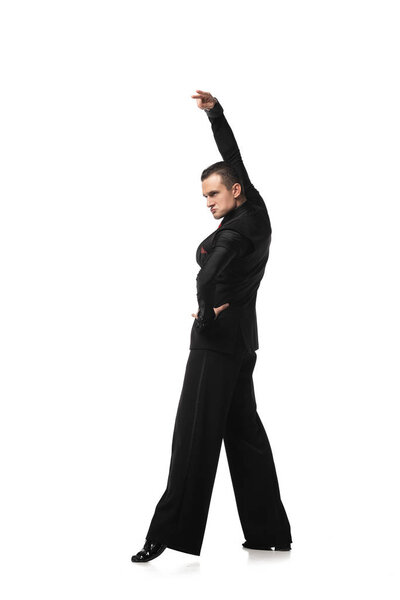 expressive dancer in elegant black suit performing tango with hand on hip on white background